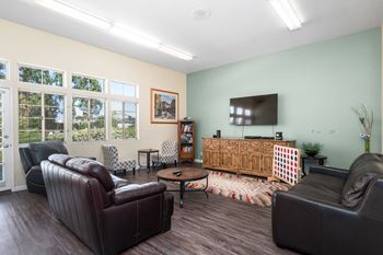 A living room with a brown leather couch, a wooden cabinet, and a flat screen TV.